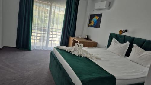 a bedroom with a green and white bed with a window at Hotel Maya in Horezu