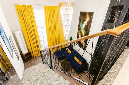 a staircase with yellow curtains and a blue chair at Andor Luxury Hotel & Duplex in Durrës