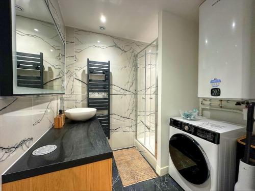 a bathroom with a sink and a washing machine at Appartement de standing tout confort, Aups in Aups