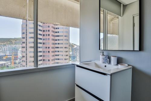 baño blanco con lavabo y ventana en D'Luxe on Thibault by CTHA, en Ciudad del Cabo