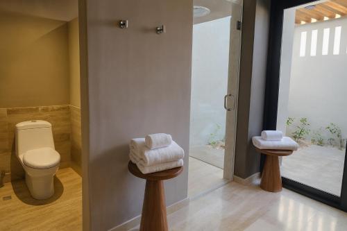 a bathroom with a toilet and two stools with towels at Hotel Flores de Sal-Valle de Guadalupe in Valle de Guadalupe