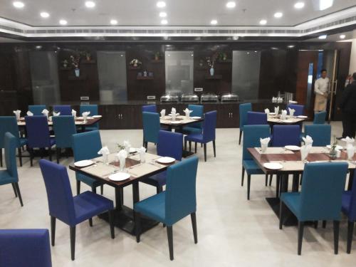 a dining room with tables and blue chairs at The Legend in Allahābād