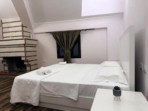a white bedroom with a bed and a fireplace at Keshtjella Duka in Rrëshen
