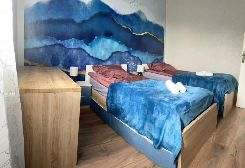 two beds in a room with a painting on the wall at Maison individuelle, 3chambres, avec parking in Le Grand-Quevilly