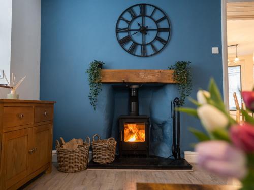 a fireplace in a living room with a clock on the wall at Garn View in Dolgellau