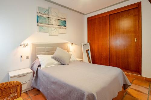 a bedroom with a white bed and a wooden door at Casa Nani in Zahara de los Atunes
