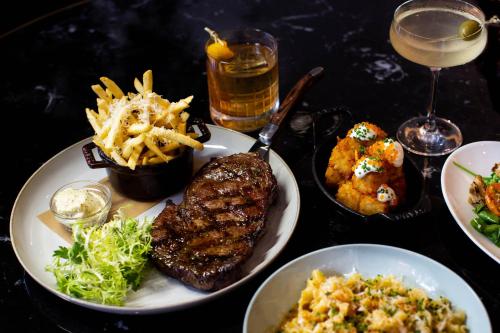 a table topped with plates of food with meat and fries at Virgin Hotels Dallas in Dallas