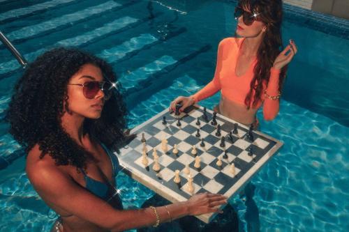 two women in a swimming pool playing chess at Virgin Hotels Dallas in Dallas