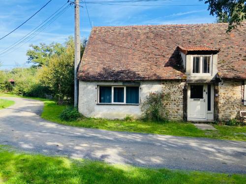an old stone house with a white door and a road at La Grange in Thollet