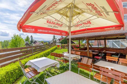 a patio with tables and chairs and an umbrella at Resort Abertham - penzion Ellen in Abertamy