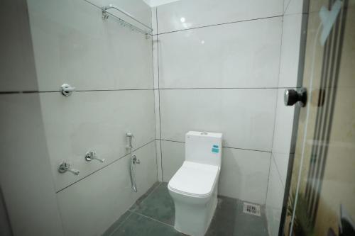 a white bathroom with a toilet and a shower at Breathe homestay in Ambalavayal