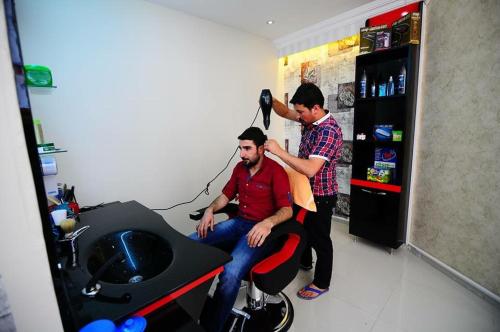 two men cutting a mans hair in a barber shop at Hotel Dosco in Van