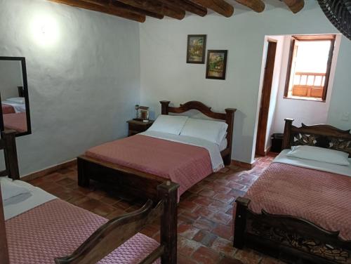 ein Schlafzimmer mit zwei Betten und einem Spiegel in der Unterkunft El Zaguan in Barichara