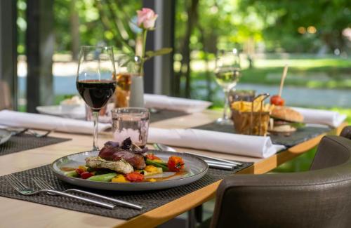 a table with a plate of food and a glass of wine at Leonardo Hotel Hannover in Hannover