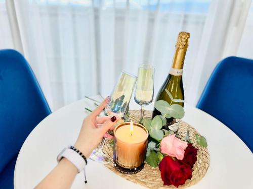 a person holding a candle and a bottle of wine on a table at ORBI CITY LUXURY deluxe KIG DVD in Batumi