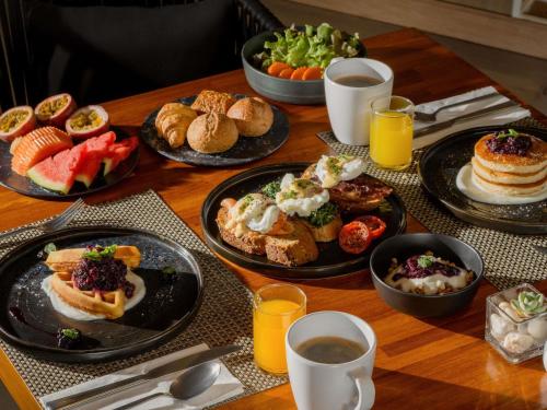 a table with plates of breakfast foods and drinks at Andaman Beach Hotel Phuket - Handwritten Collection in Patong Beach