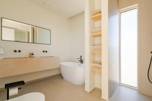 Un baño con bañera, lavabo y espejo. en New Villa - Rooftop Jacuzzi & Sunset Views, en Santa Bárbara de Nexe