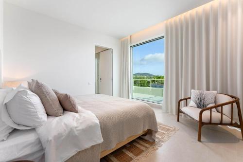 Un dormitorio con una cama, una silla y una ventana en New Villa - Rooftop Jacuzzi & Sunset Views, en Santa Bárbara de Nexe