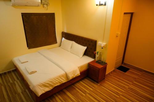 a small bedroom with a bed with white sheets at Raindrop Homestay Havelock in Sir William Peel Island