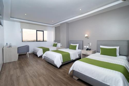 a room with three beds with green and white sheets at Hotel Plaza Monte Carlo in Guayaquil