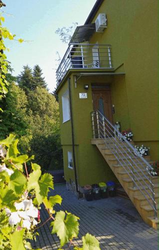 a green building with a staircase leading up to a door at Zakątek u Poety Dąbrówka in Jasło