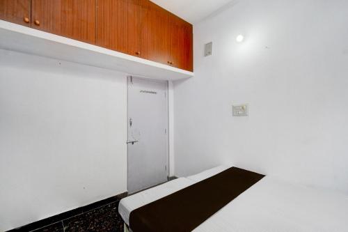 a white room with a bed and a cabinet at Hotel O Sun Lodge in Hyderabad