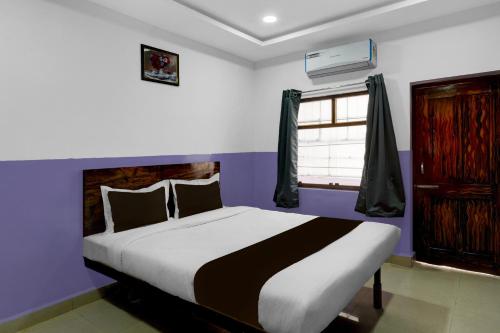 a bedroom with a bed with purple walls and a window at Hotel O P R S Elite in Surūrnagar