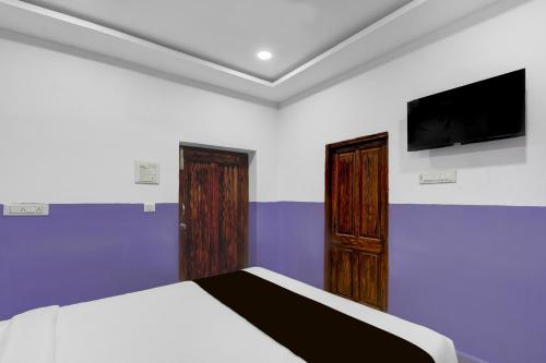 a bedroom with a bed and a flat screen tv at Hotel O P R S Elite in Surūrnagar