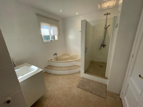 a white bathroom with a tub and a sink at Charming villa in Nerja in Nerja