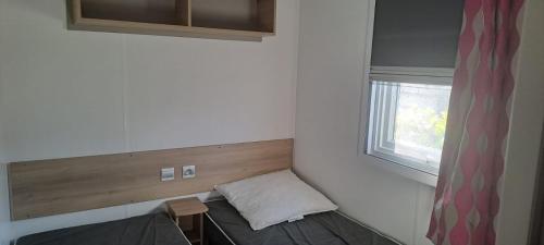 una piccola stanza con un letto e una finestra di Mobil home 3 chambres 2 sdb 282 a Pont-Aven