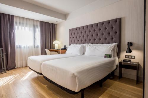 a hotel room with a large bed with a large headboard at Zenit Abeba in Madrid