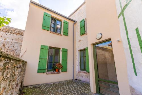 a house with green shutters and a courtyard at L'authentique, Chic, relaxant et entrée autonome in Coulommiers