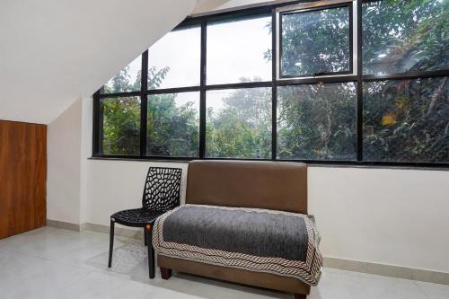a room with a couch and a chair and windows at Hotel O Avaanti in Pune