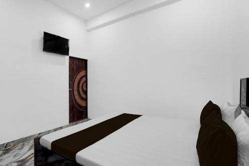 a bedroom with a white bed with a black stripe on it at SPOT ON Hotel Golden Tree in Agra