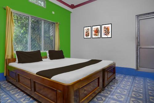 a bed in a room with a green wall at Hotel O Trinayani Homestay in Mādāri Hāt