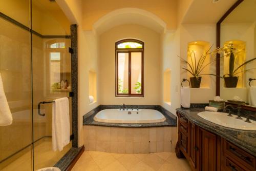 a bathroom with a tub and two sinks and a window at Casa Garmus 10 bdrs ocean views in Los Suenos in Herradura