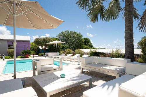 a patio with white chairs and an umbrella and a pool at Villa Azur in Saint-François