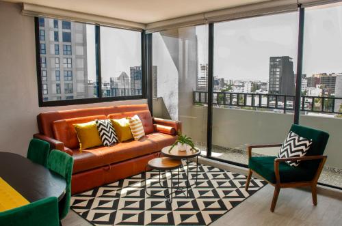 a living room with a couch and chairs and windows at Cozy Apartment in Chapultepec with Gym, Rooftop & Parking in Guadalajara