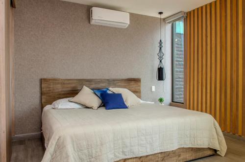 a bedroom with a large bed with blue pillows at Cozy Apartment in Chapultepec with Gym, Rooftop & Parking in Guadalajara