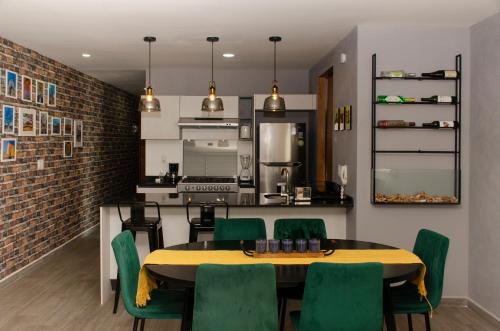 a kitchen and dining room with a table and green chairs at Cozy Apartment in Chapultepec with Gym, Rooftop & Parking in Guadalajara