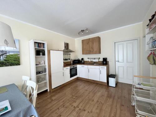 a kitchen with white cabinets and a wooden floor at Alte Heimat in Schwegenheim