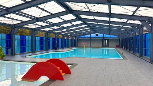 a swimming pool with red chairs in a building at Casa Vida Verde - Luxe vakantiewoning aan het water! in Gramsbergen