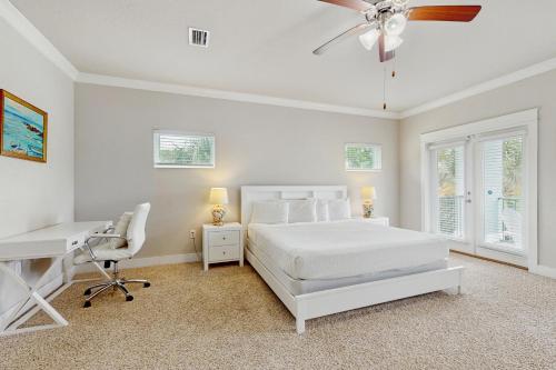 a white bedroom with a bed and a desk at Stella Maris in Perdido Key