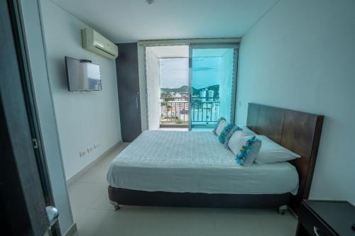 ein Schlafzimmer mit einem Bett und einem großen Fenster in der Unterkunft Rodadero Gaira - Apto con piscina a 2 cuadras de la playa in Rodadero