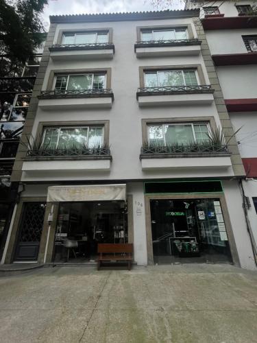 a white building with windows and a bench in front at MIIRO Hotel in Mexico City