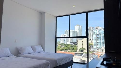 a bedroom with two beds and a large window at Exclusivo Aparta Suite en el Rodadero Ideal para 4 pax in Santa Marta