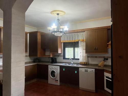 cocina con armarios de madera, lavadora y secadora en Cortijo Algüit, en Vélez Blanco