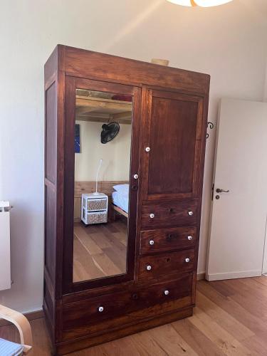 a wooden cabinet with a mirror in a room at Humus Sapiens 2 in Tavarone