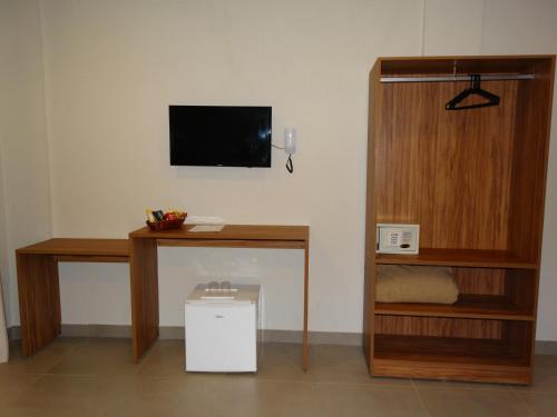 a room with a desk and a tv on a wall at Pousada Tropicarim in Itacimirim