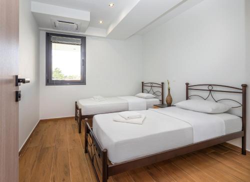 two beds in a room with white walls and wooden floors at arvangroup-apartments in Nafpaktos